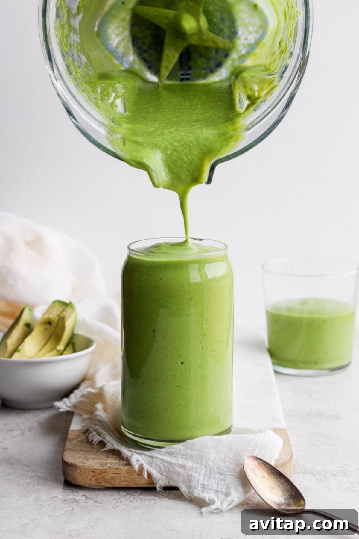 The Ultimate 4-Ingredient Avocado Smoothie Creamy avocado smoothie being poured from a blender into a clear glass, ready to be enjoyed.