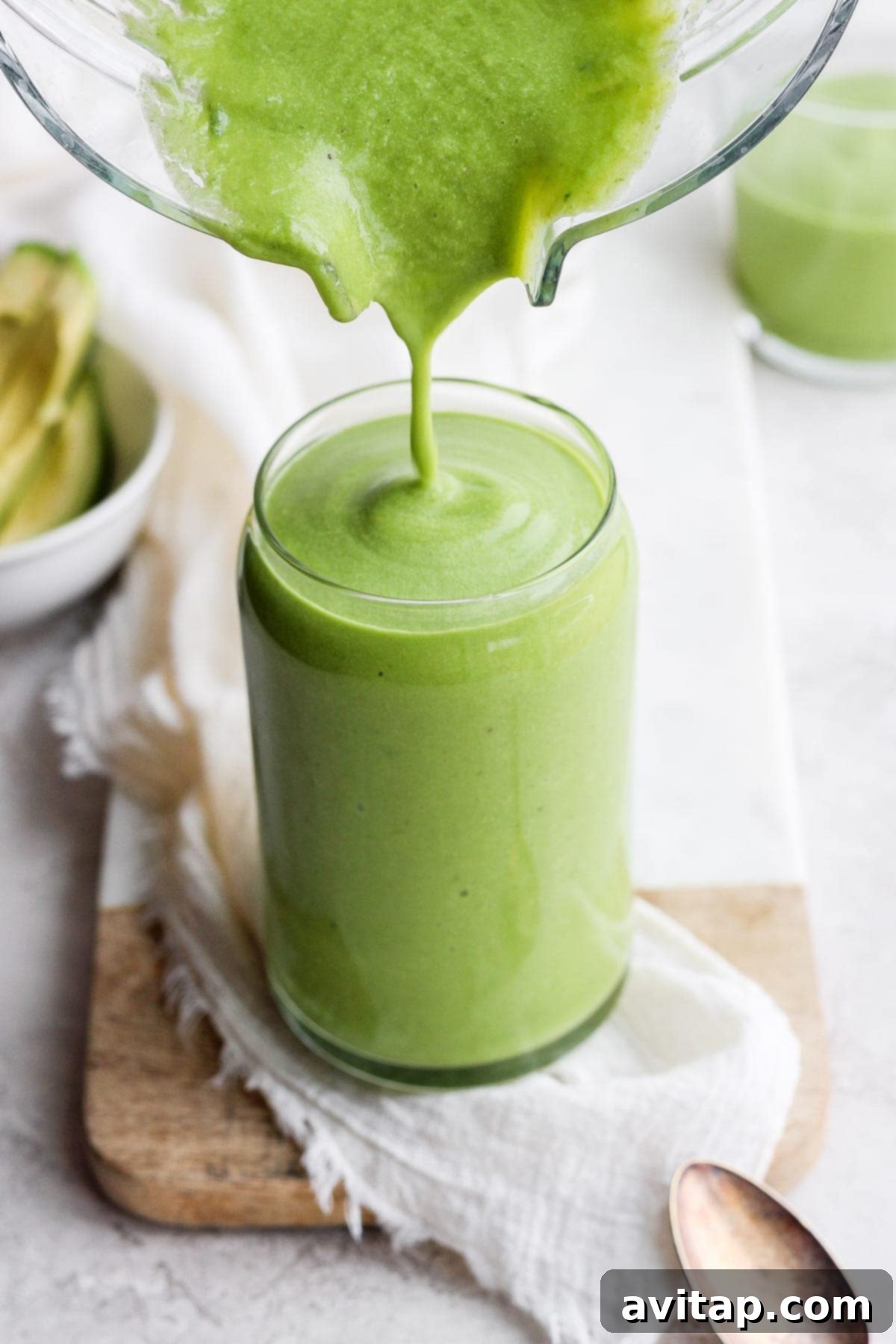 Freshly Blended Avocado Smoothie The finished avocado smoothie being poured smoothly into a serving glass from a blender, showcasing its creamy texture.