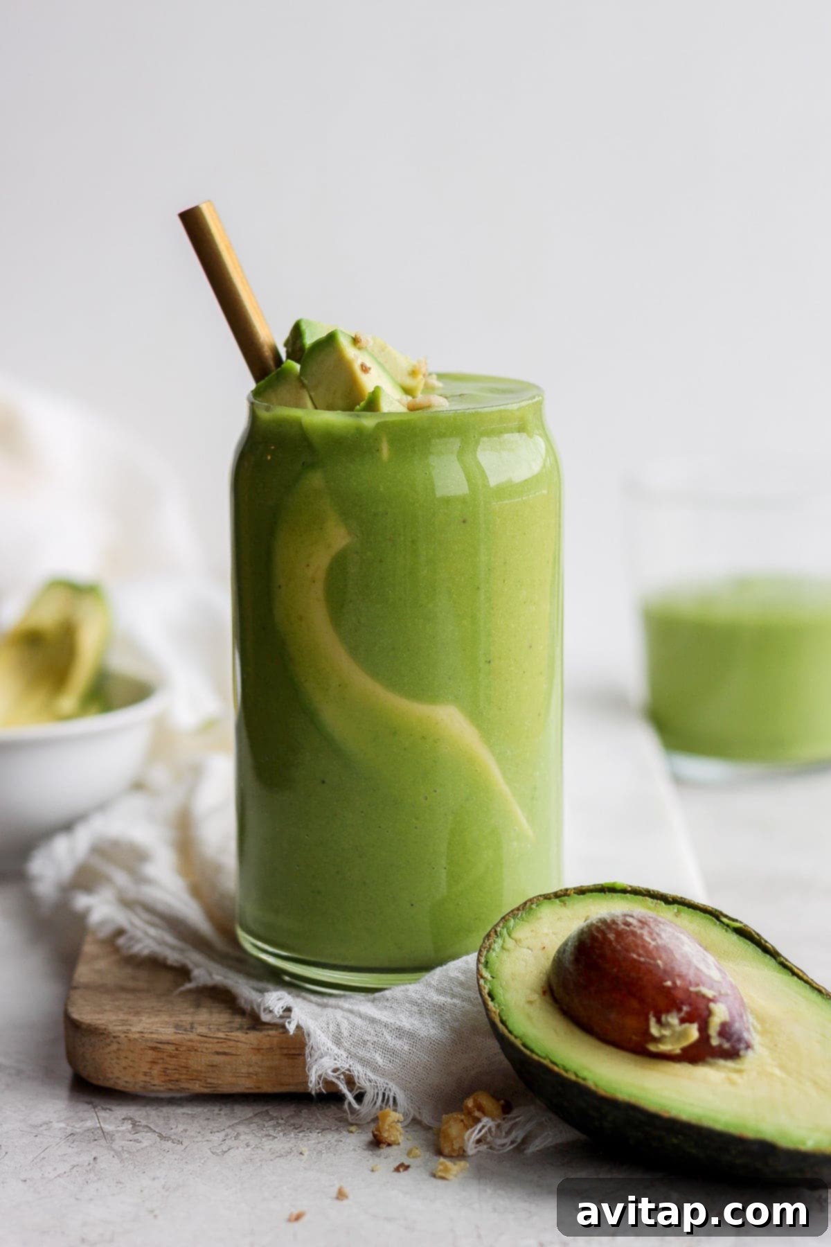 Avocado Smoothie with Healthy Toppings Avocado smoothie garnished with fresh avocado slices and a sprinkle of hemp hearts in a tall glass, showcasing a healthy and appealing presentation.