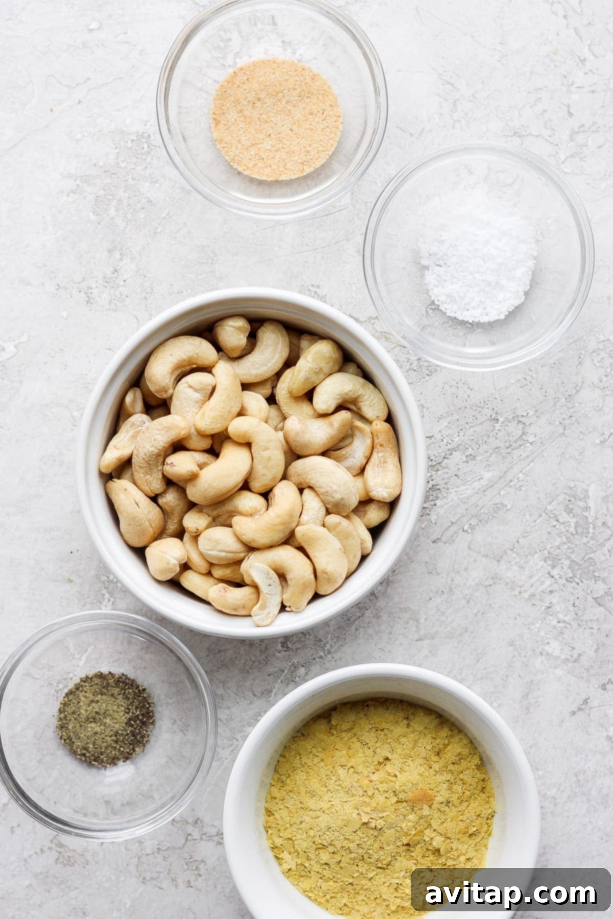 All five ingredients for vegan parmesan cheese laid out on a clean surface, ready for blending in a food processor.