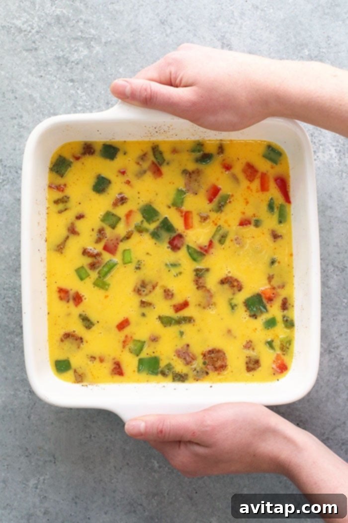 Uncooked chicken fajita breakfast casserole in a baking dish, ready to go into the oven