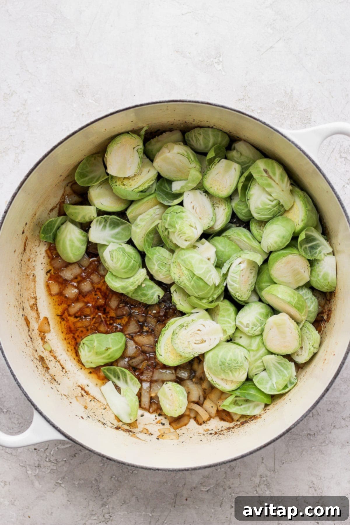Fresh Brussels sprouts and chopped onion ready to be sautéed in a Dutch oven.