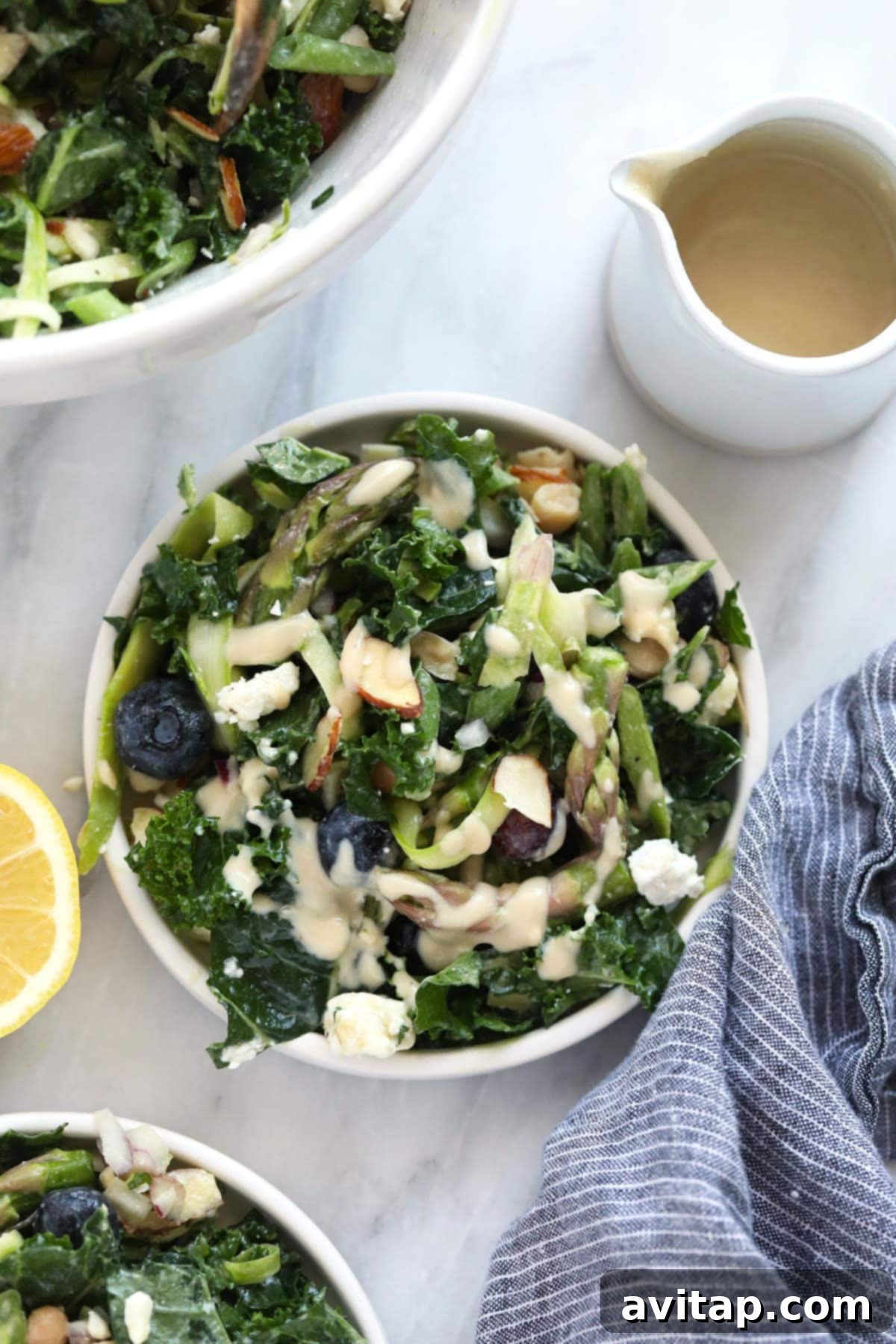 Vibrant Asparagus Salad 2 A vibrant bowl of asparagus salad featuring shaved asparagus, kale, and a side of creamy hummus dressing.