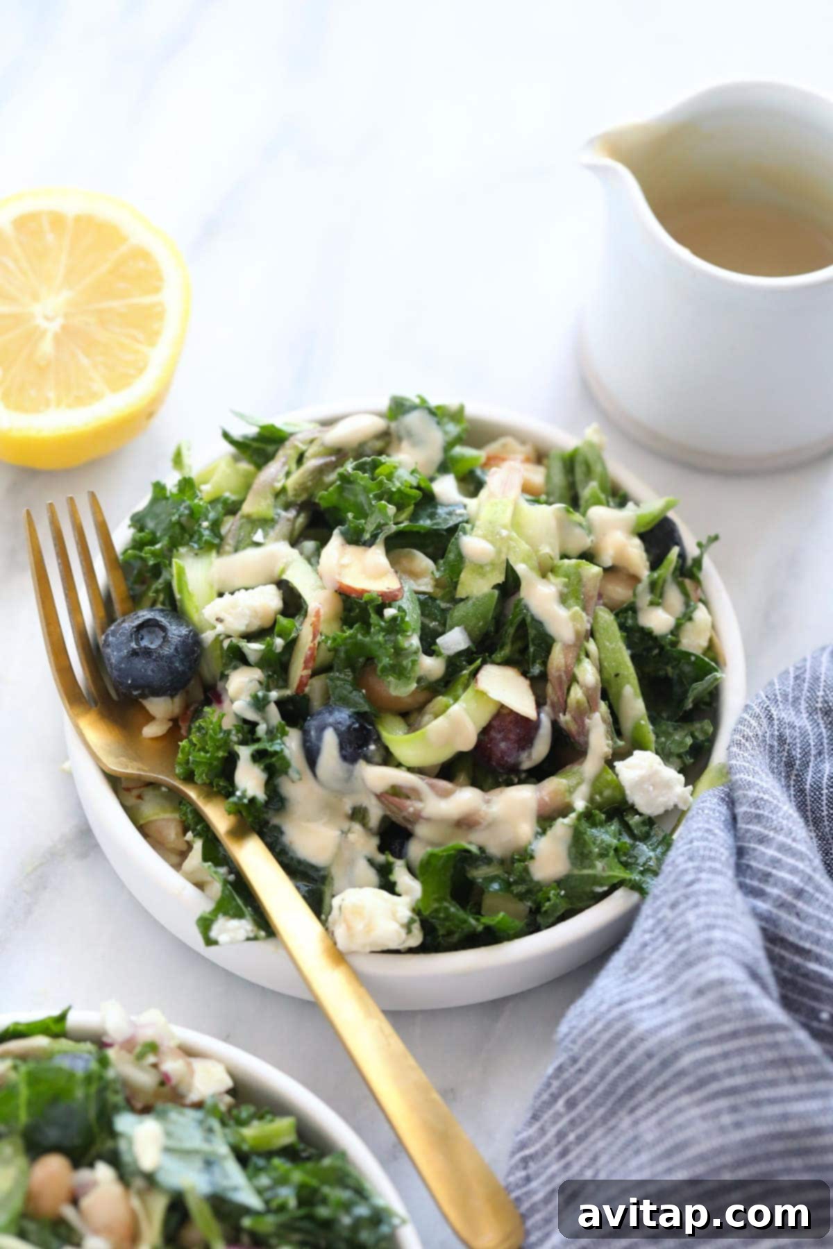 A close-up shot of a generous serving of asparagus salad in a white bowl, highlighting the texture of the shaved asparagus and the vibrant colors of the other ingredients.