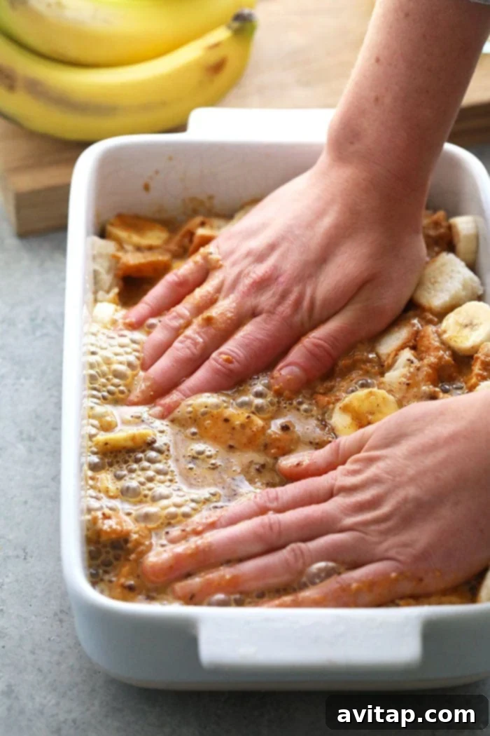 Hands serving a slice of Peanut Butter Banana French Toast Bake from a casserole dish.
