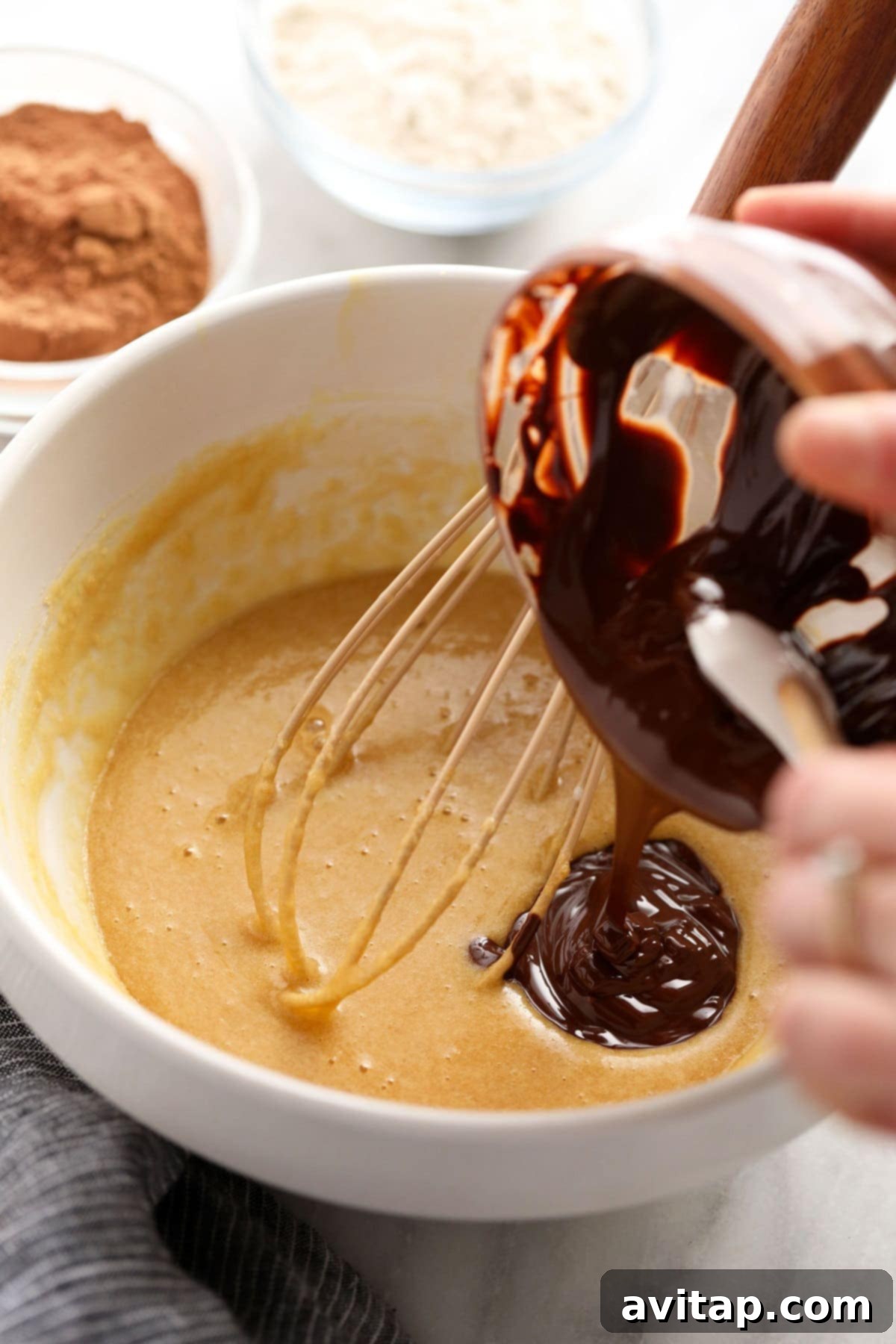Melted chocolate being poured into brownie batter, enhancing the rich chocolate flavor.