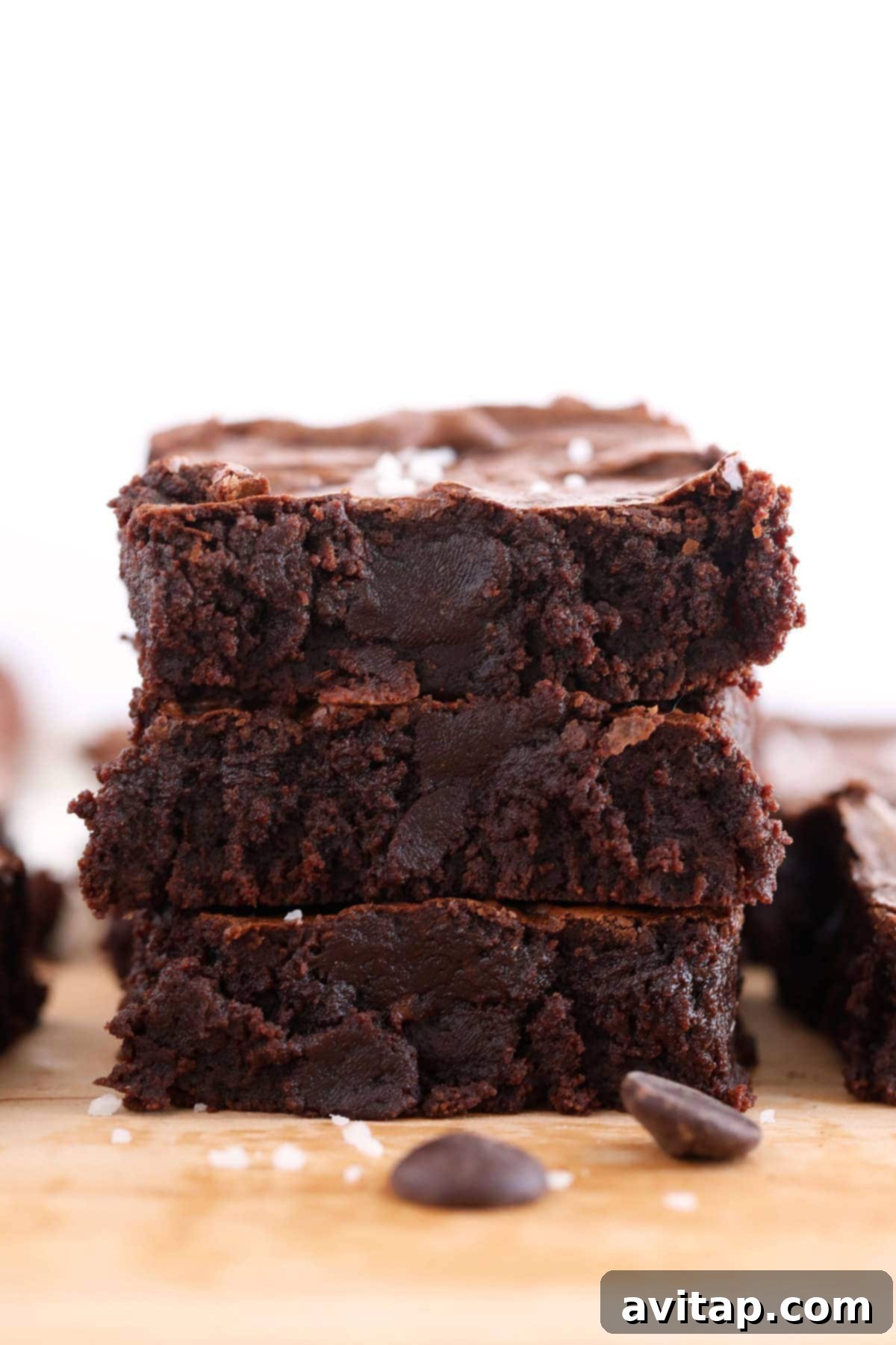 Three decadent fudgy brownies stacked on top of each other, showcasing their rich texture.