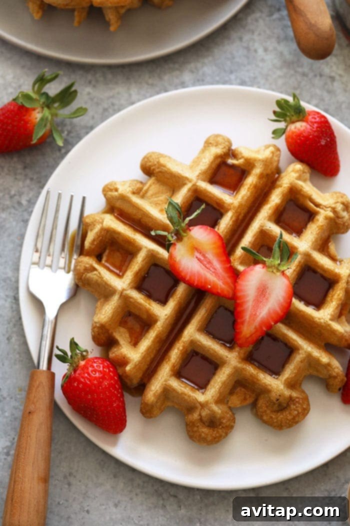 Healthy protein waffles on a plate, topped with fresh berries and maple syrup