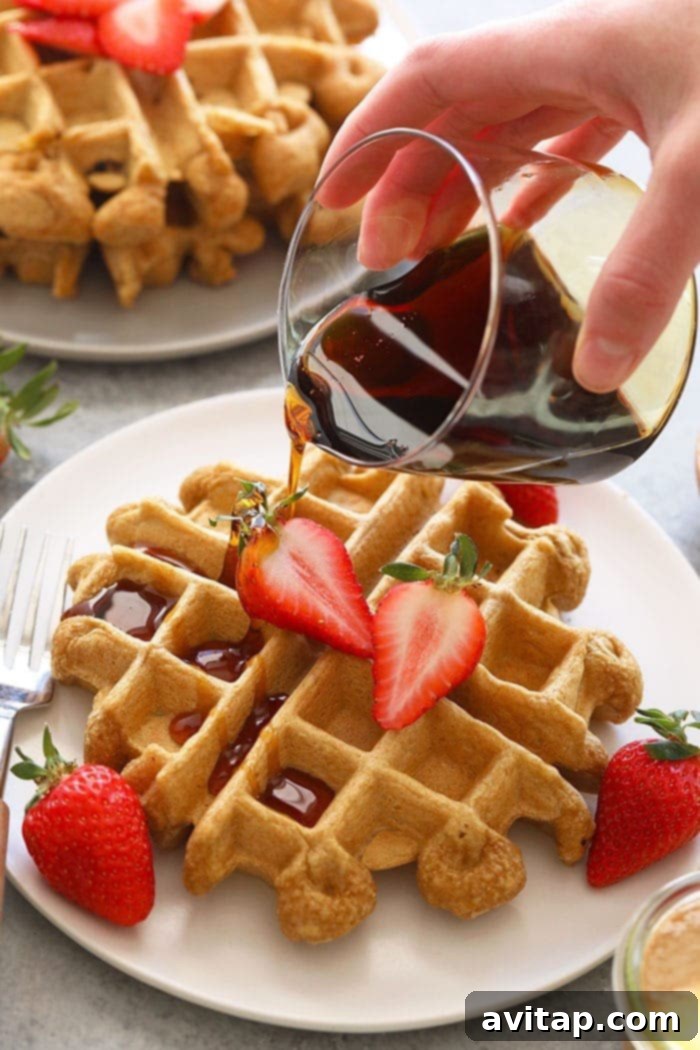 Healthy protein waffles topped with fresh fruit and a drizzle of maple syrup