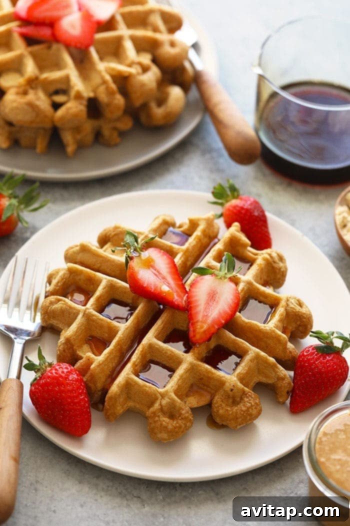 Healthy protein waffles on a plate with berries and maple syrup