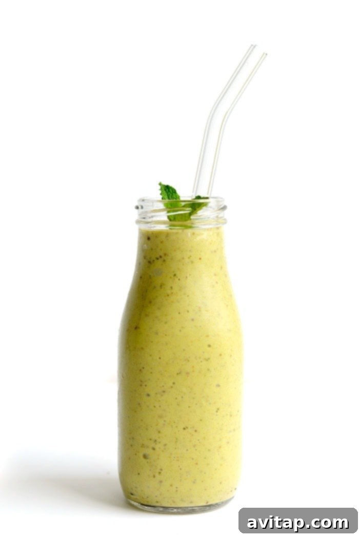 A photo of an avocado banana smoothie in a glass with a straw