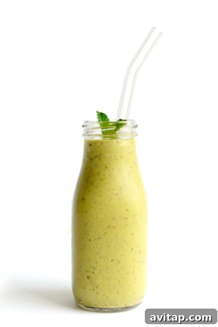 A vibrant green avocado banana smoothie in a glass with mint leaves and avocado slices, ready to be enjoyed.
