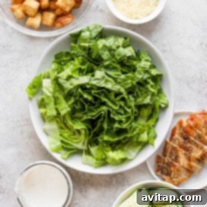 A mix of fresh salad ingredients including crisp romaine, golden croutons, and refreshing cucumber in a large bowl, ready for assembly.