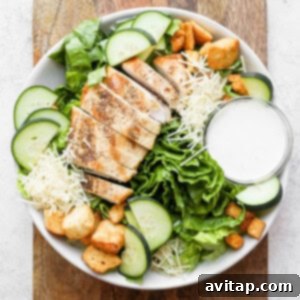 A vibrant chicken Caesar salad with golden croutons and rich dressing in a white bowl, ready to be enjoyed as a hearty meal.