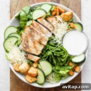 A vibrant salad featuring chicken, romaine lettuce, and fresh cucumbers.