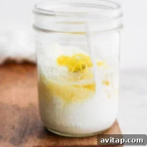 A jar of lemon yogurt on a cutting board, ready for mixing.