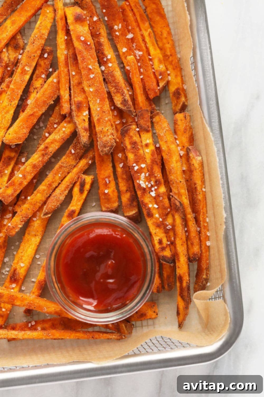 A close-up shot of perfectly golden and crispy baked sweet potato fries, seasoned to perfection.