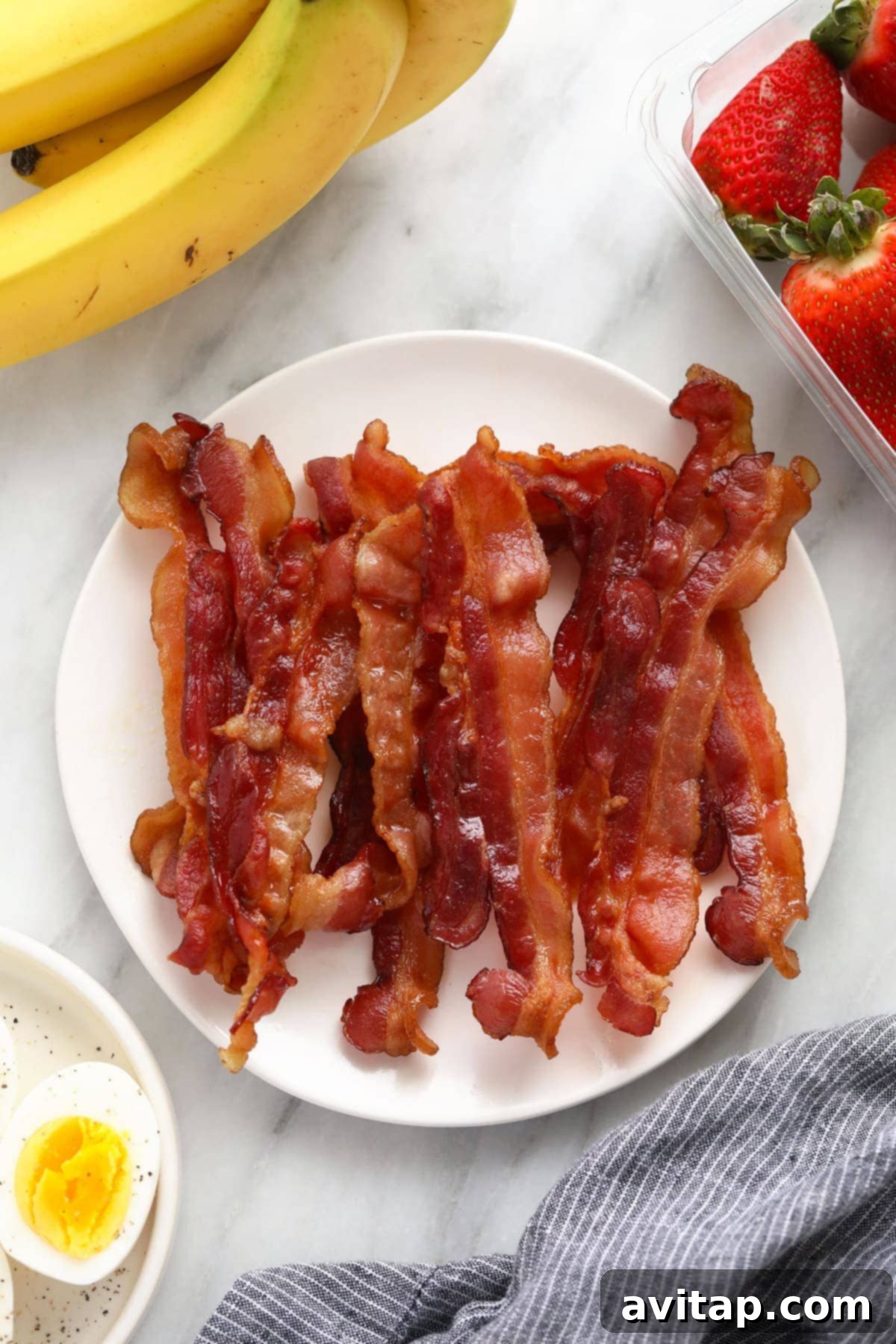 A beautifully arranged pile of golden, crispy bacon strips on a plate, ready to be enjoyed.