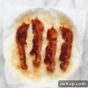 Cooked bacon strips cooling on a plate, ready to be enjoyed.