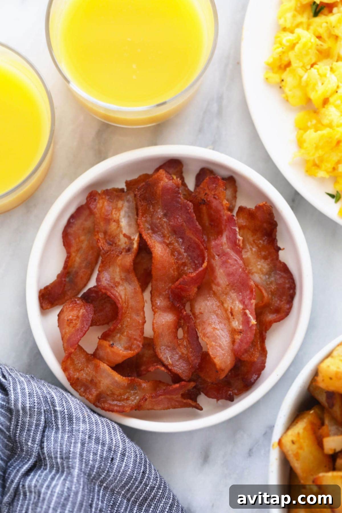 Perfectly cooked crispy bacon on a white plate, ready to be served for a delicious breakfast.