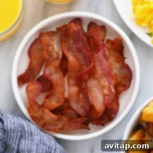 Cooked bacon strips perfectly arranged on a plate, highlighting their golden-brown crispiness.