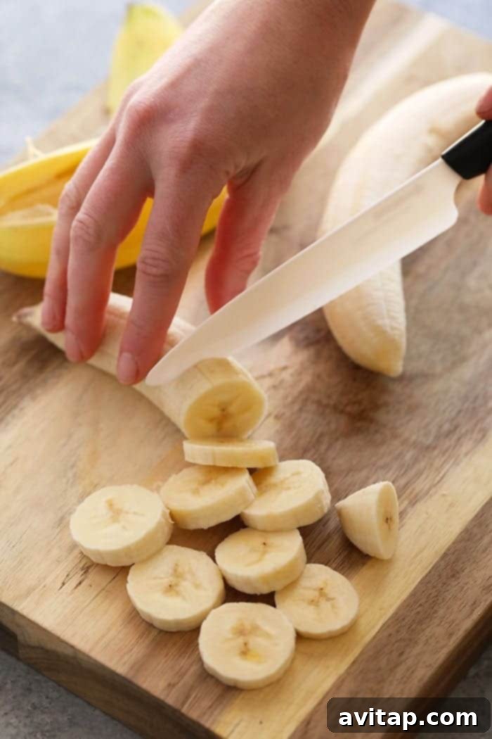 Slicing a banana for nice cream on a wooden cutting board, highlighting preparation.