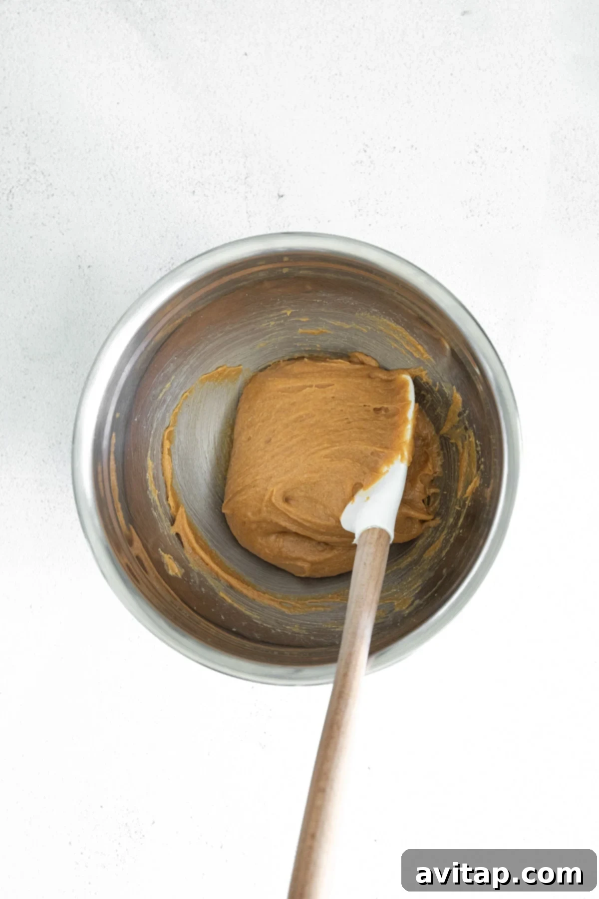 A bowl filled with smooth, creamy peanut butter, ready to be incorporated into the cookie dough.