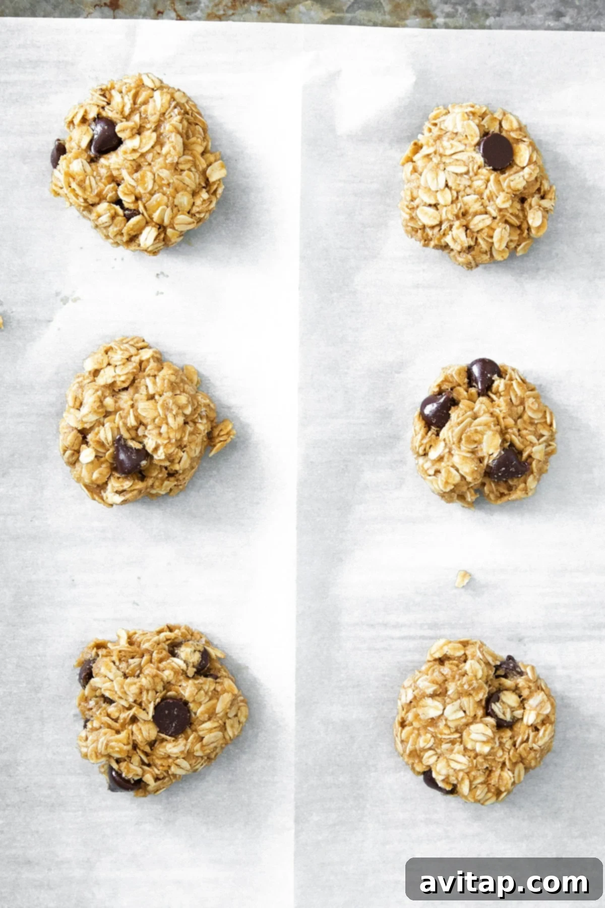 Freshly baked peanut butter oatmeal cookies cooling on a baking sheet, with golden-brown edges and soft interiors.