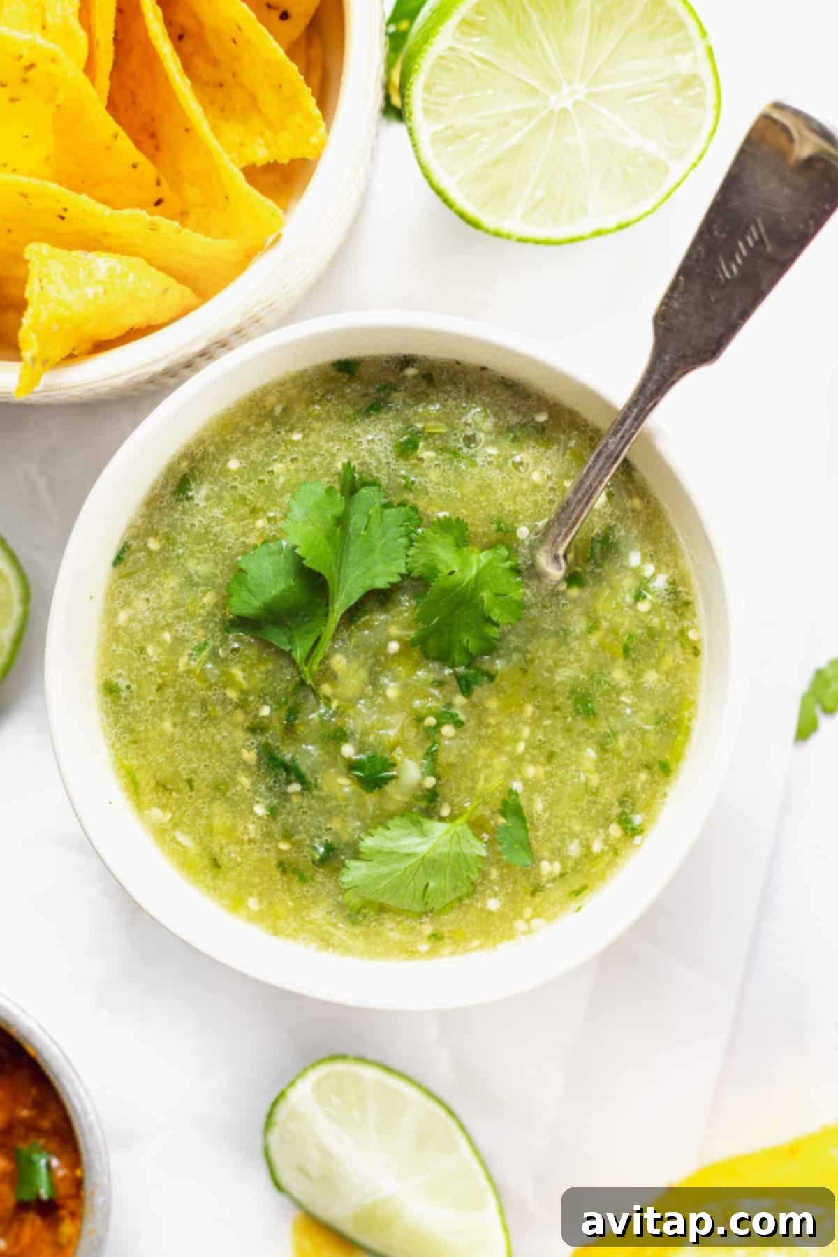 A bowl of vibrant green salsa verde, garnished with fresh cilantro, ready to be enjoyed with tortilla chips.