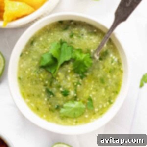A close-up of a bowl of vibrant green salsa verde, garnished with fresh cilantro.