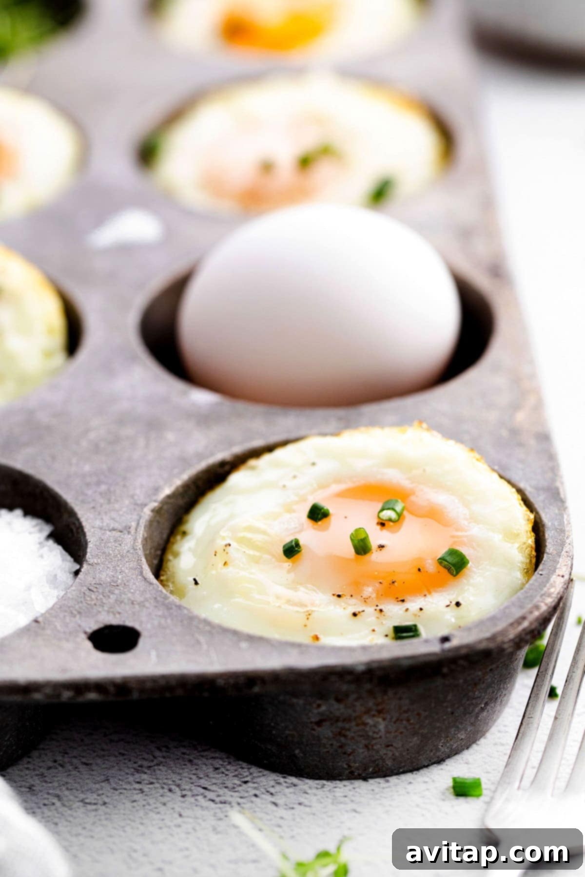 Golden baked eggs neatly nestled in a nonstick muffin tin, ready to be enjoyed.