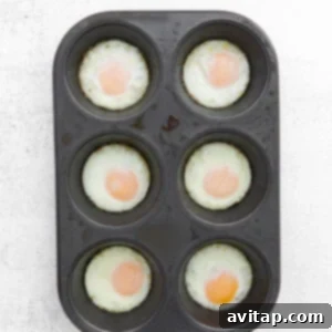 Cooked baked eggs in a muffin tin, illustrating different doneness levels achieved through varying bake times.