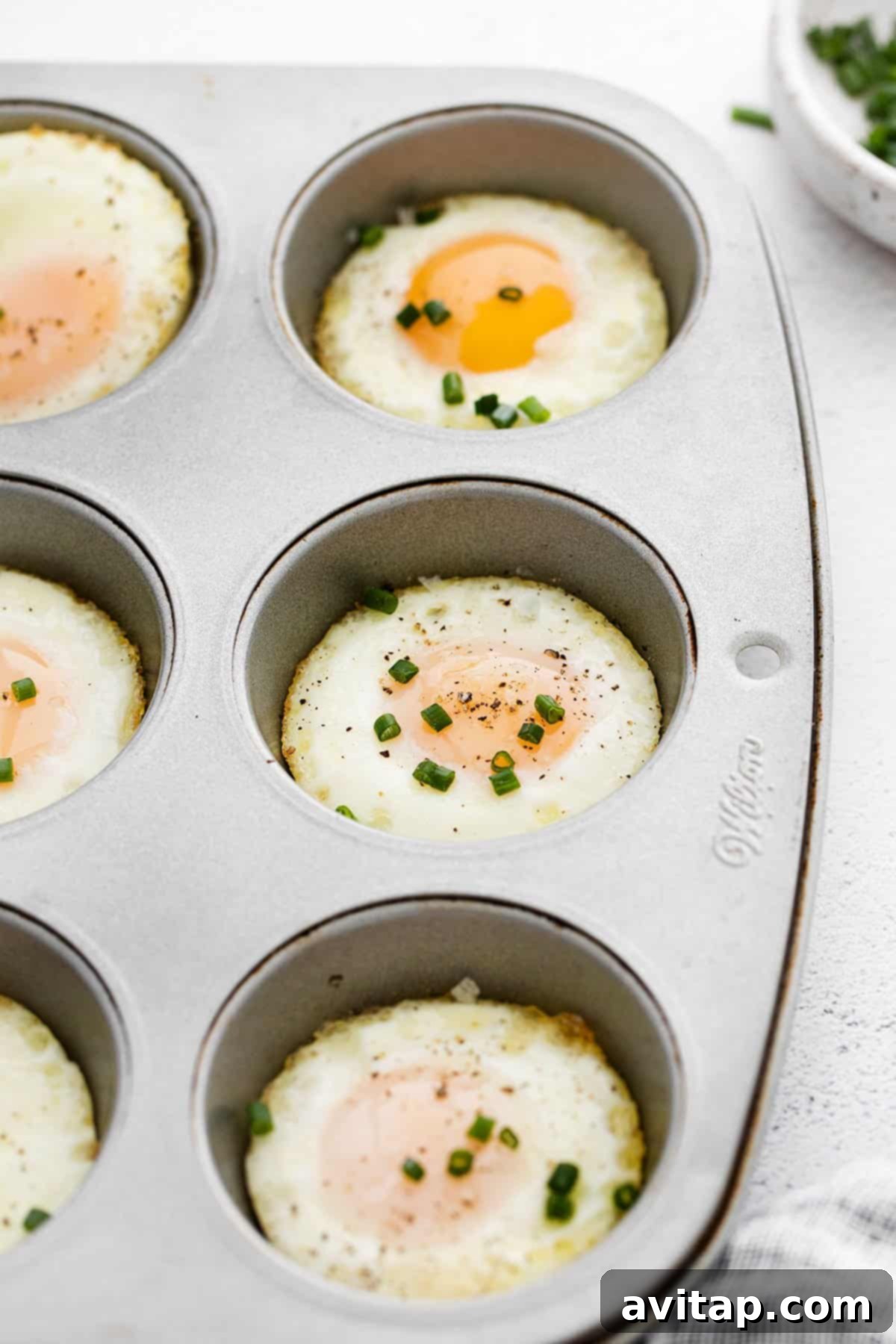 Step-by-step instructions for baking eggs in the oven using a muffin tin, garnished with fresh chives.