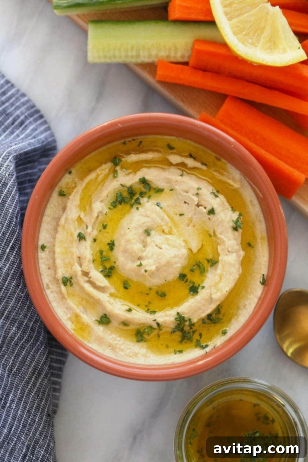 Vibrant lemon garlic hummus served in a rustic bowl, garnished with fresh herbs and a drizzle of olive oil, ready for dipping