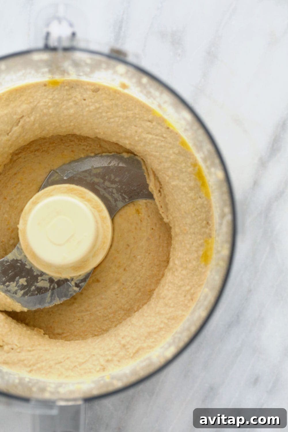 Close-up of creamy lemon garlic hummus being blended to perfection in a food processor, showing the smooth texture
