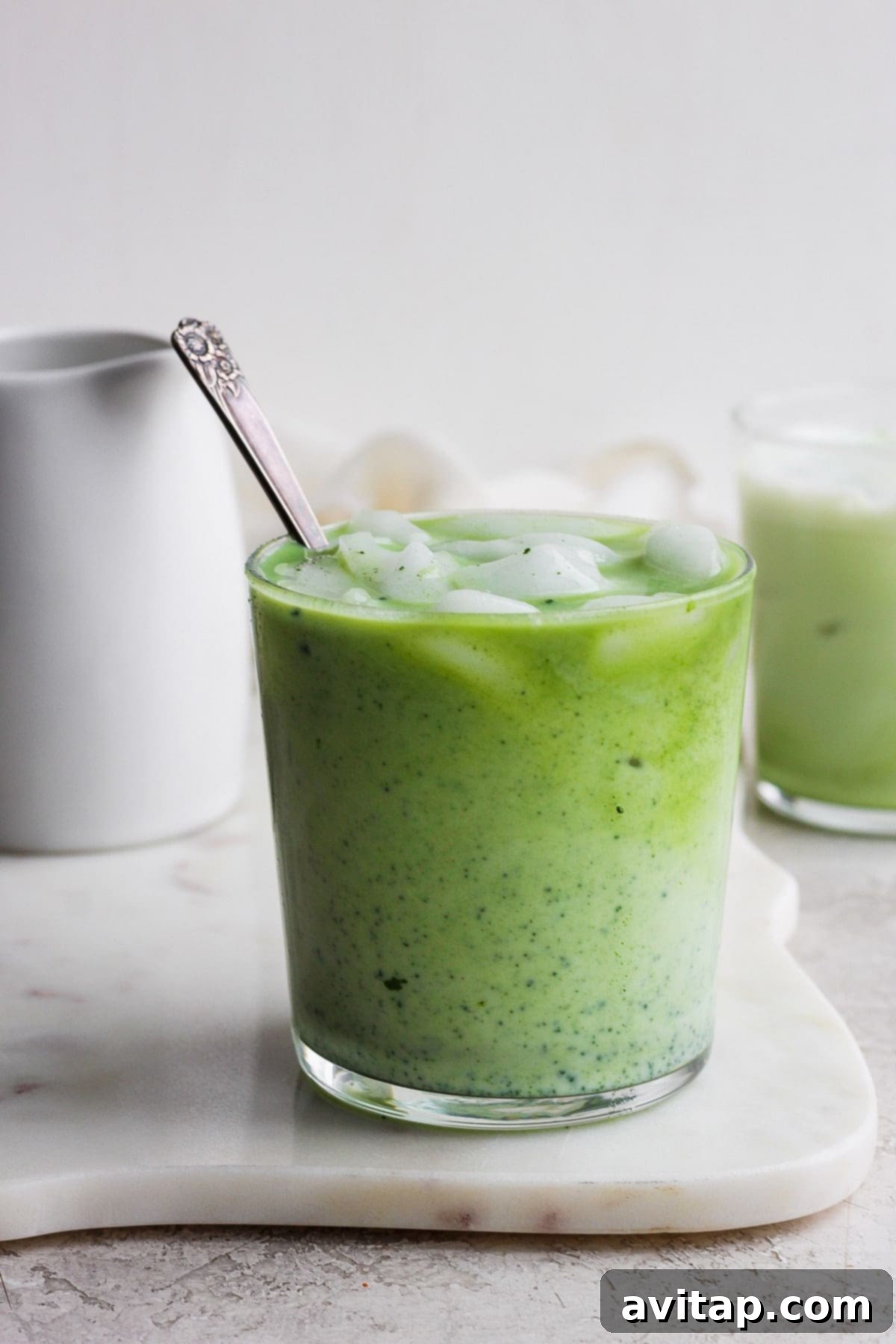A refreshing iced matcha latte with visible layers of green matcha and creamy milk, garnished with a straw, inviting a sip.