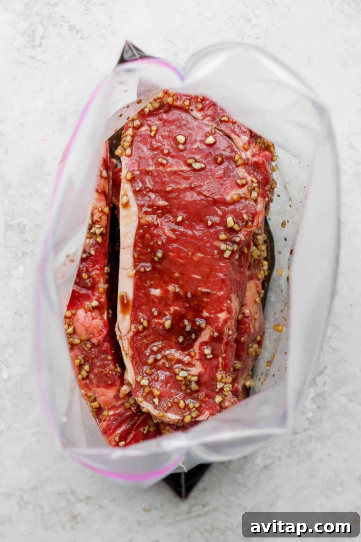 Steaks soaking in marinade inside a transparent plastic bag, ready for cooking.