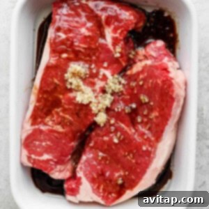 Steak marinating in a dish.