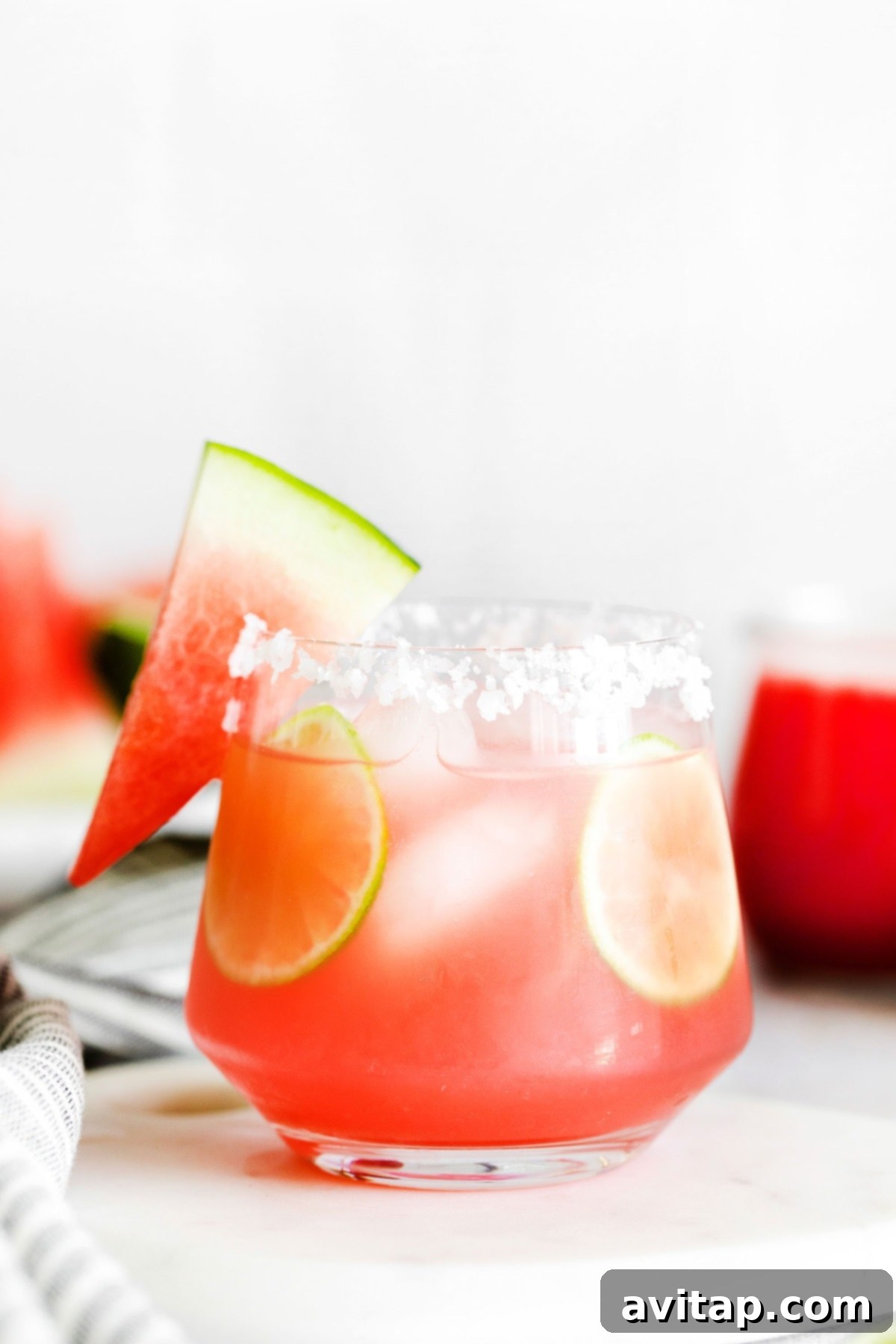 A vibrant watermelon margarita served in an elegant glass, garnished with a fresh slice of watermelon on the rim.