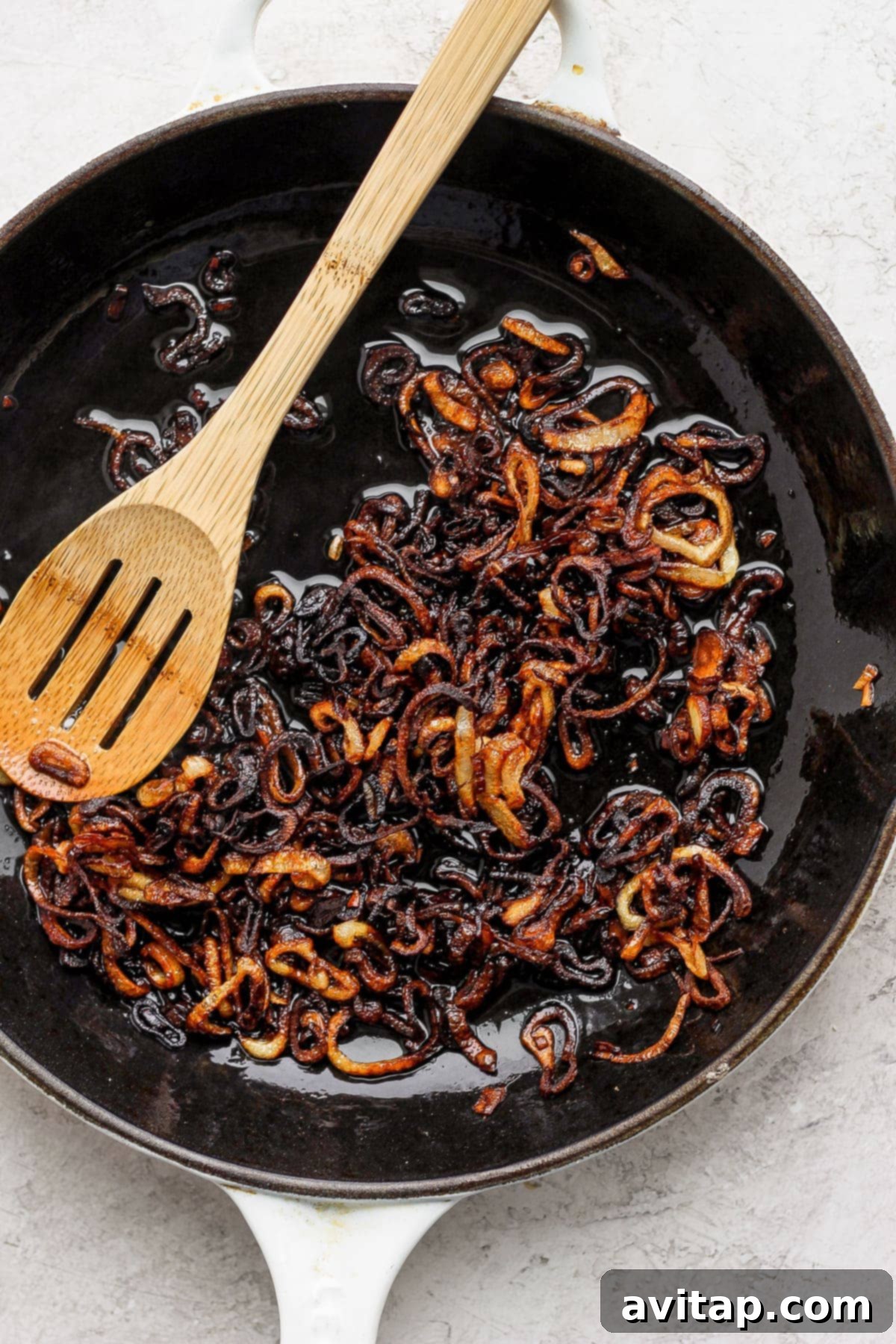 Thinly sliced shallots frying gently in a pan of olive oil until golden brown and crispy.