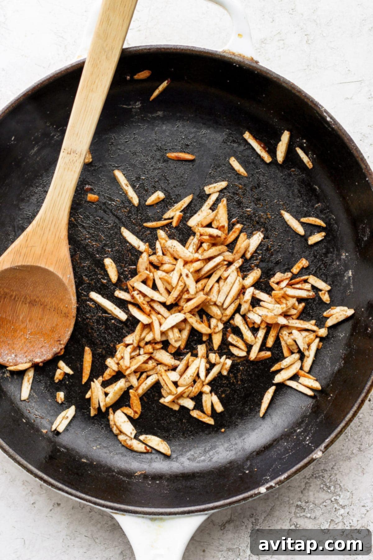 Slivered almonds gently toasting and candying in a small pan with maple syrup.