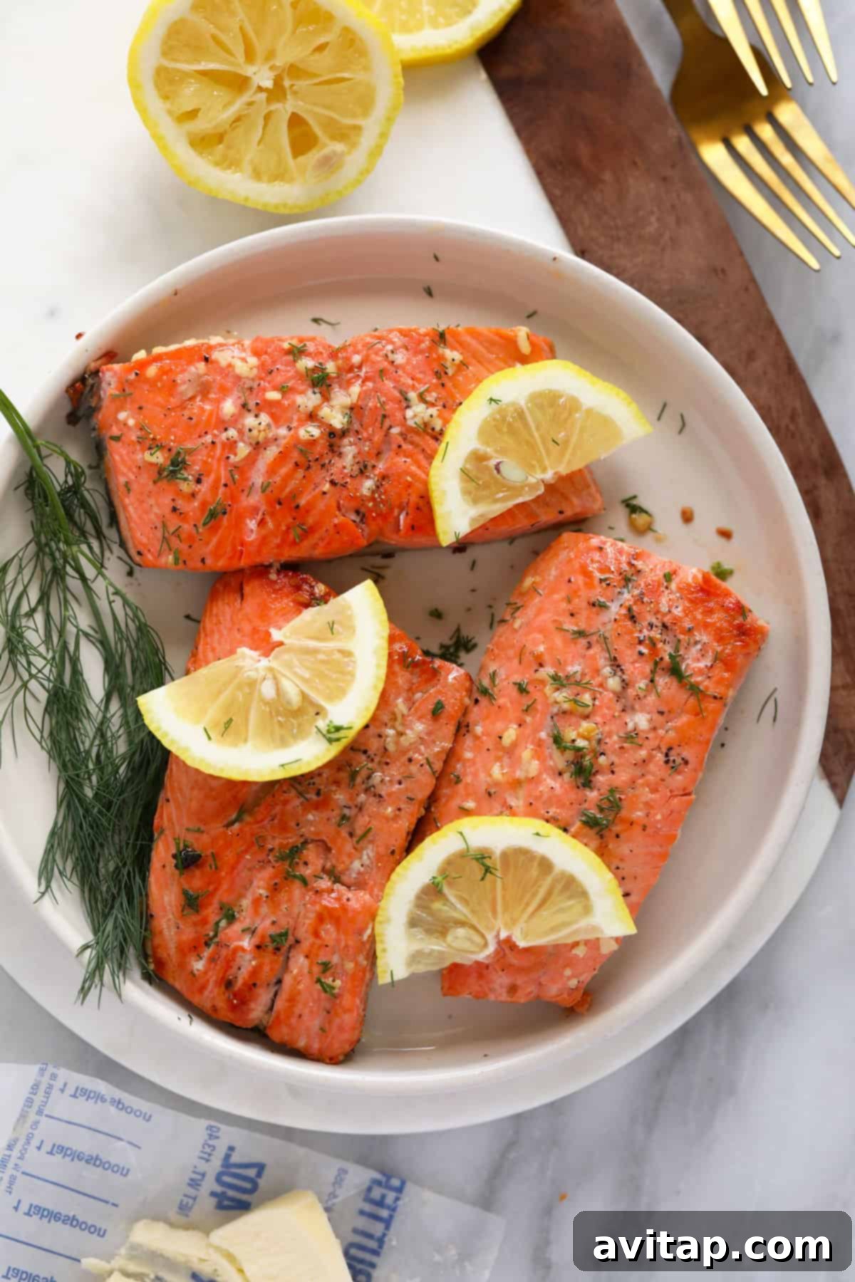 Perfectly cooked, golden-brown salmon fillets resting on a clean white plate, glistening and ready to be flaked into a delicious salad.