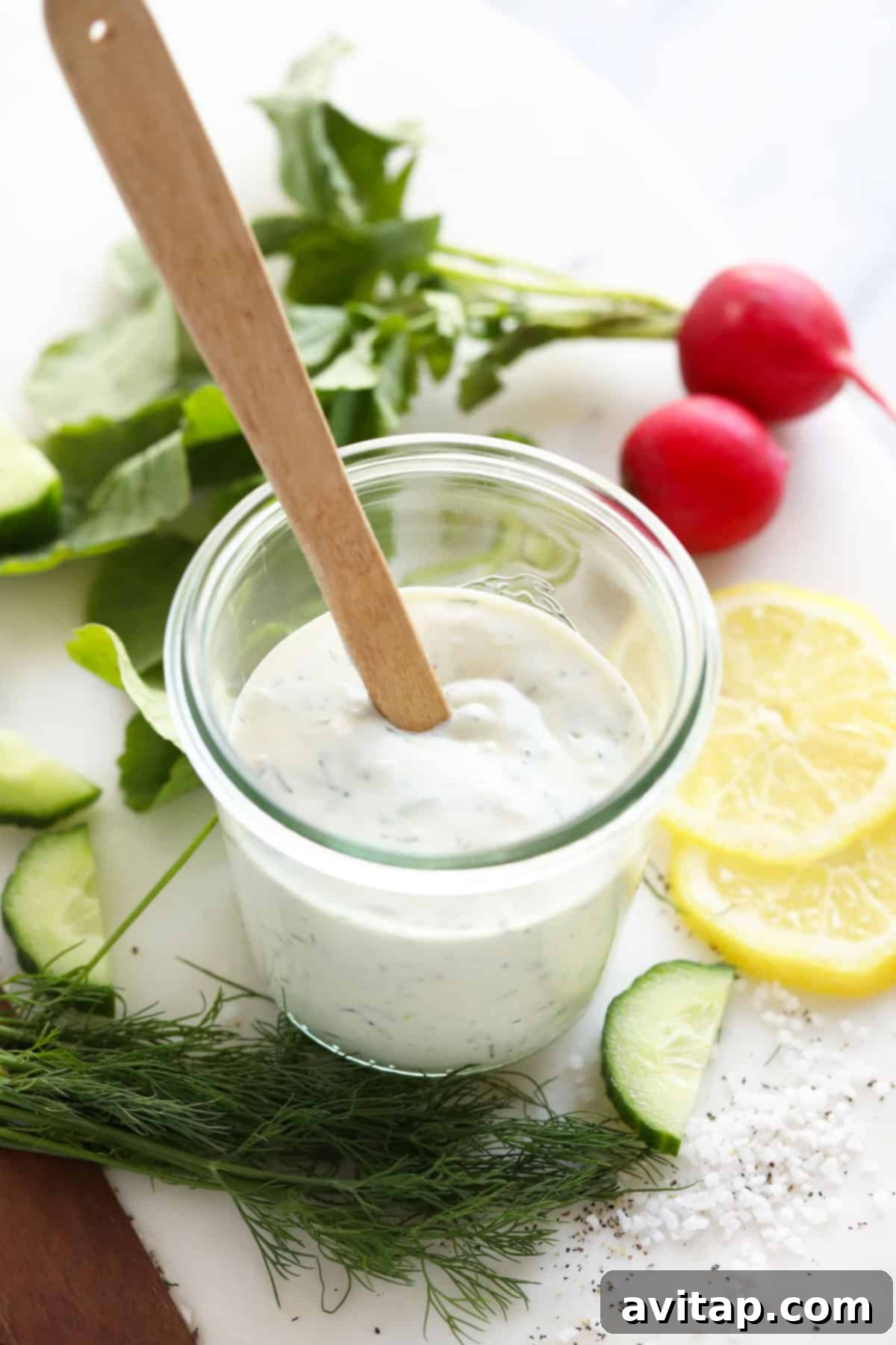 A beautiful, creamy Greek yogurt dill dressing presented in a clear glass jar, garnished with vibrant fresh dill sprigs, ready to be served or stored.