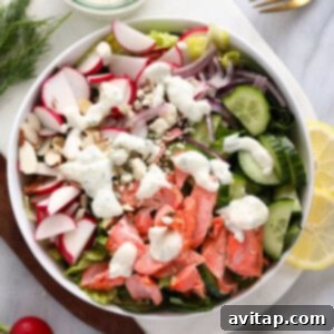 Salmon salad served in a white bowl with radishes, cucumbers, and fresh dill.