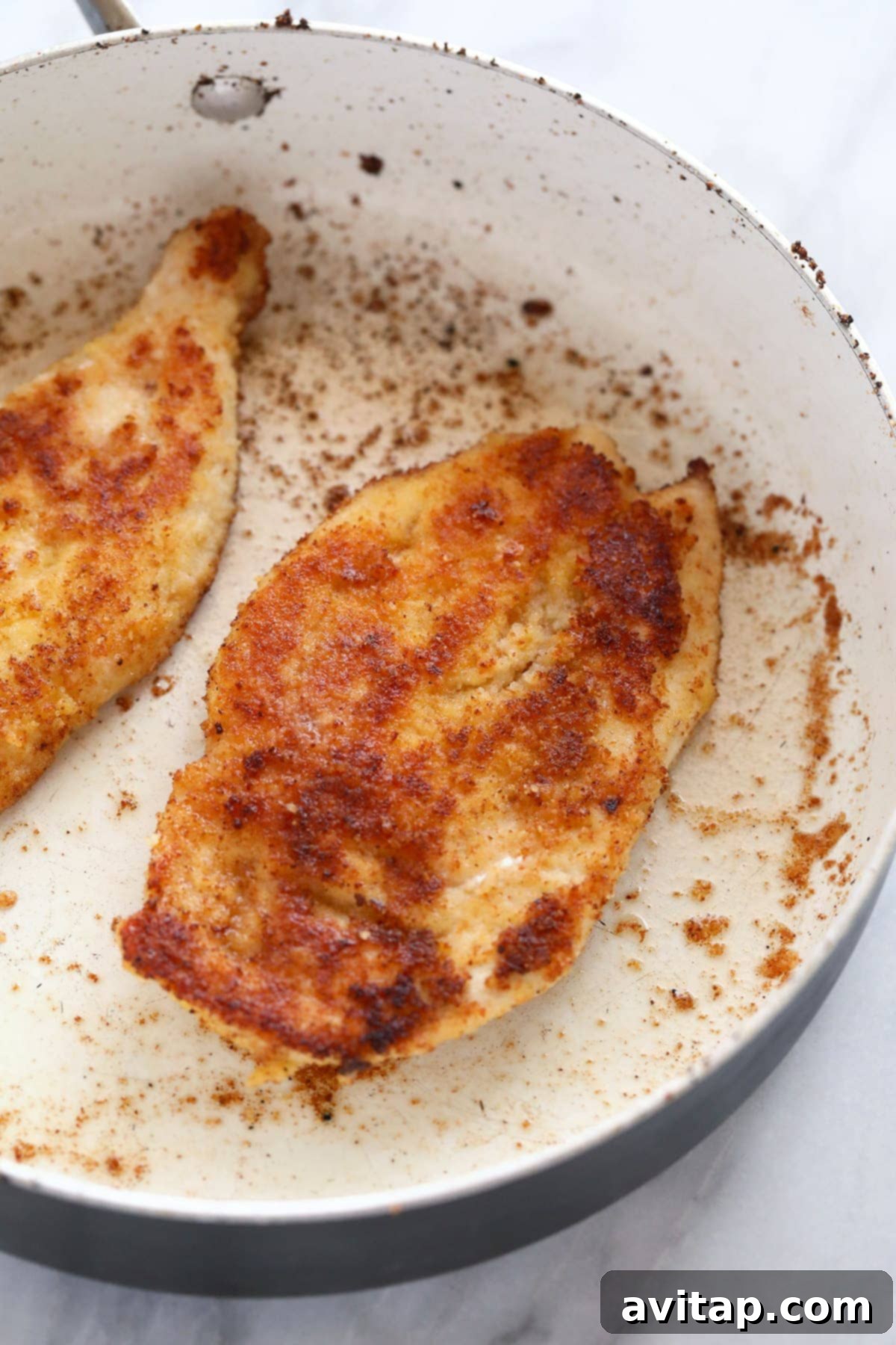 Golden Parmesan Chicken 7 Close-up shot of crispy Parmesan crusted chicken cooking in a nonstick skillet, achieving a perfect golden-brown color during pan-frying.