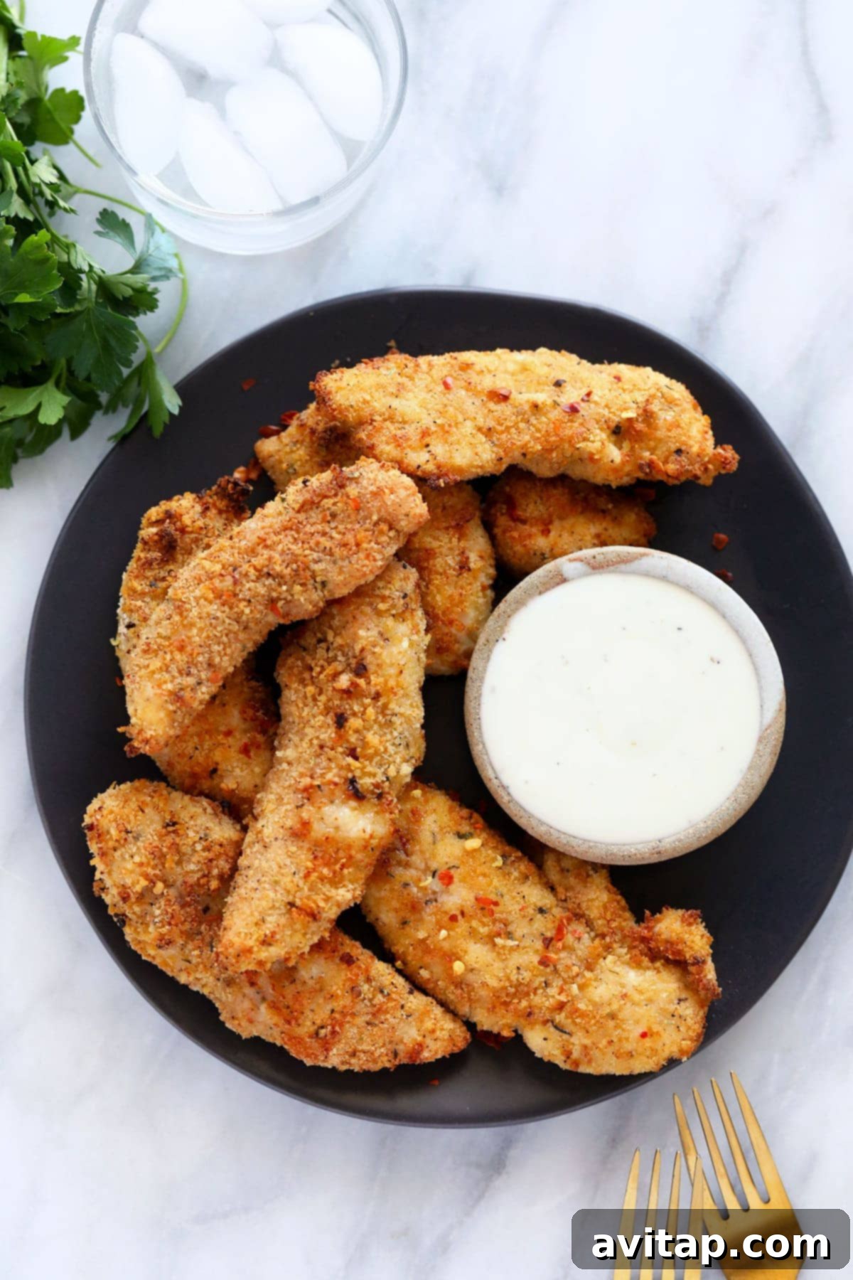 Plated air fryer chicken tenders garnished with fresh parsley, served with ranch dipping sauce