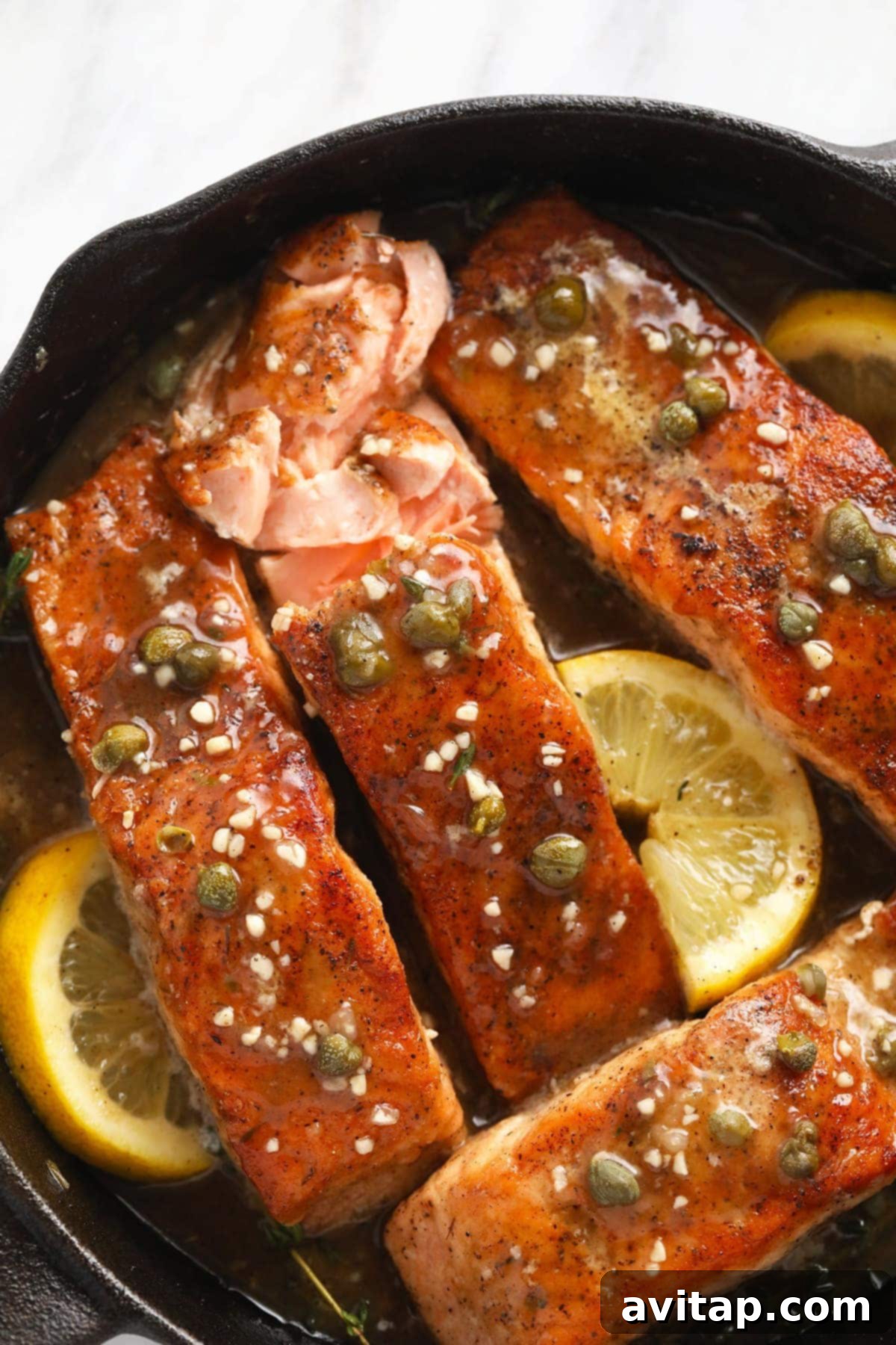 Zesty Lemon Caper Salmon 7 A vibrant salmon piccata dish, beautifully plated in a cast iron pan with fresh lemon slices, capers, and garlic, ready to serve.