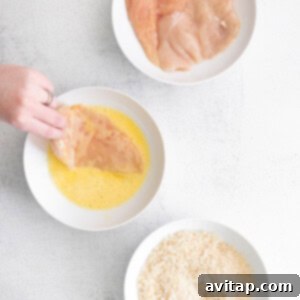 Dipping chicken into egg wash before breading.