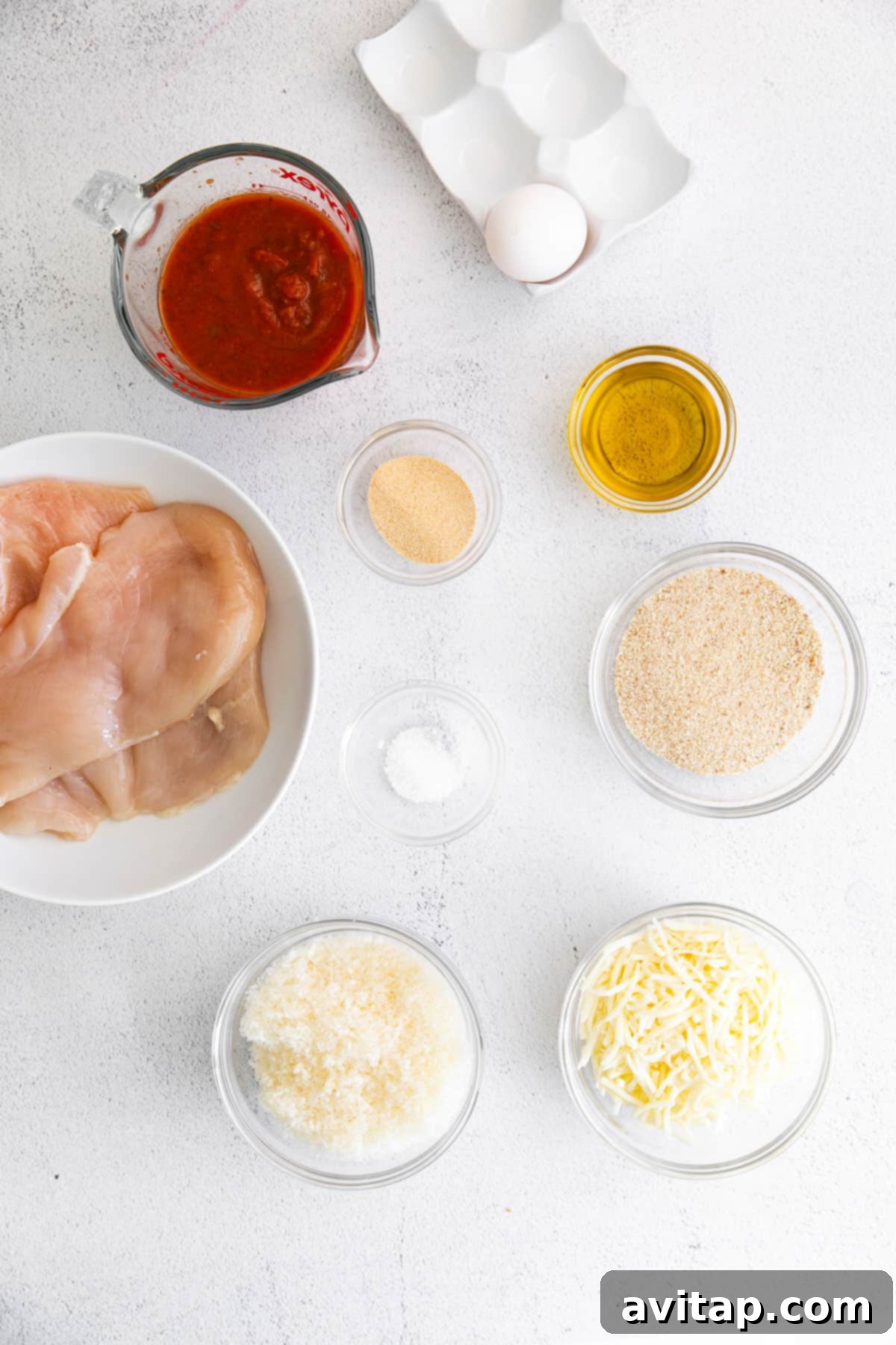 Fresh ingredients laid out on a countertop for making chicken parmesan.