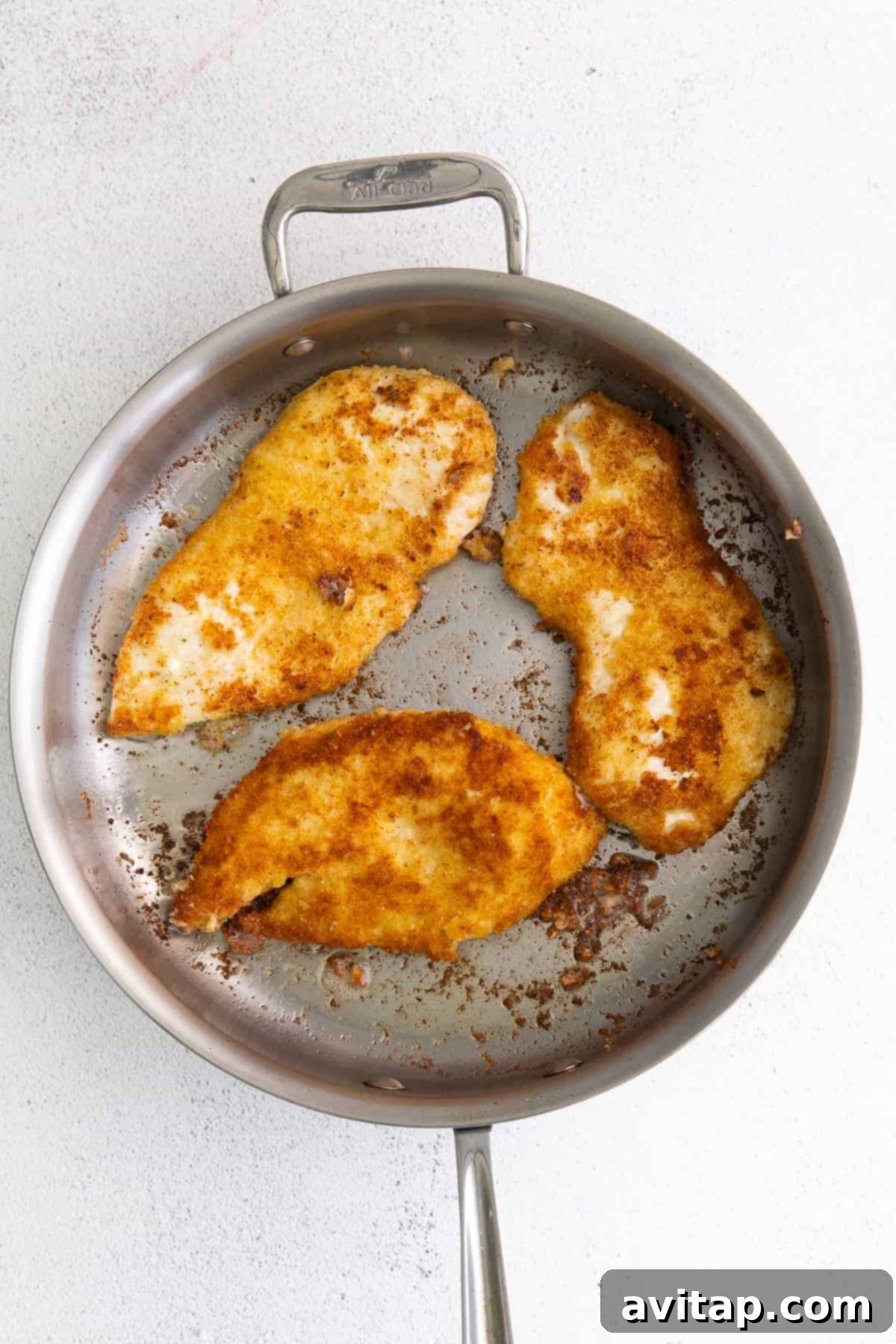 Parmesan-crusted chicken cutlets sizzling in a frying pan.